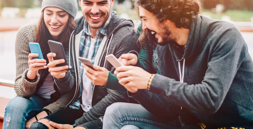 Group of smiling young people using smartphones.