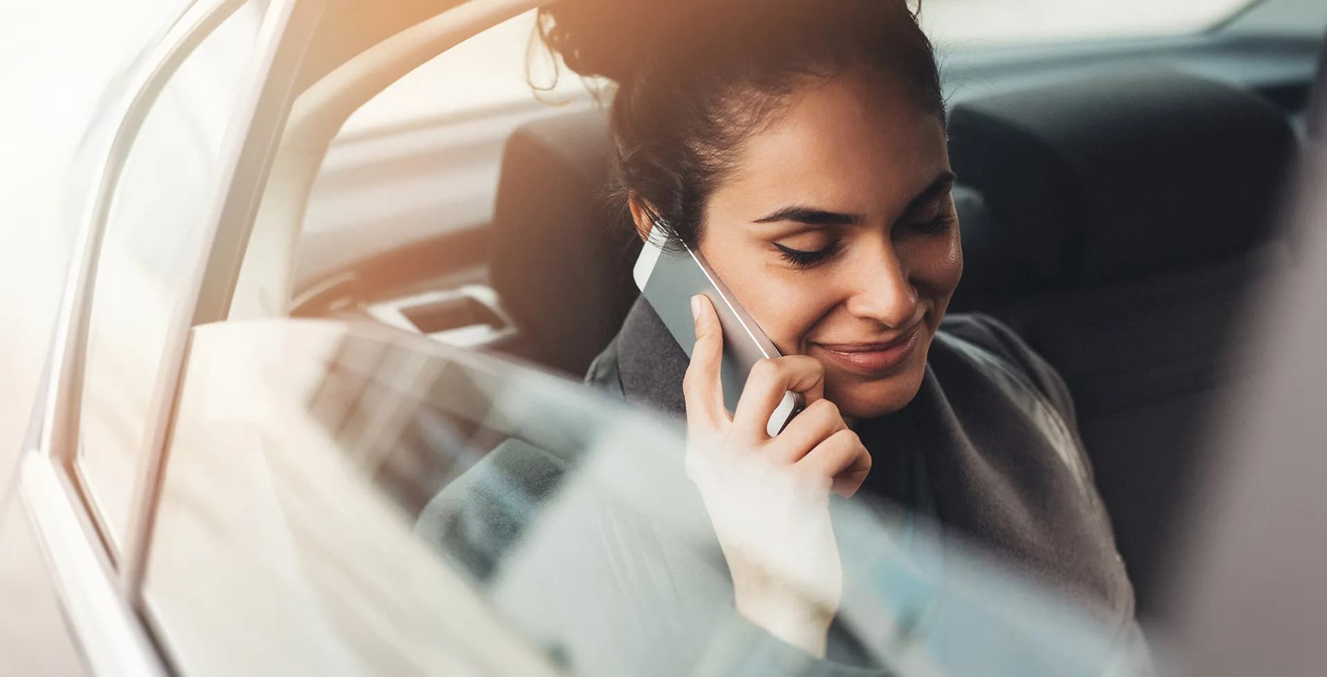 Femme d'affaires souriante utilisant son téléphone dans la voiture.