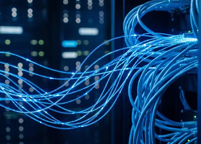 Fibres optiques bleues lumineuses devant des baies de serveurs.