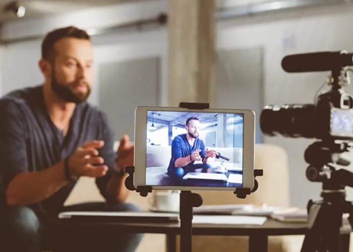 Un homme enregistre une vidéo, surveillée sur une tablette.