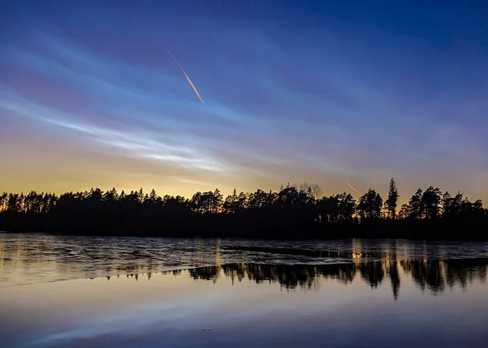 Nachtlandschaft mit Satellitenspur am Himmel.
