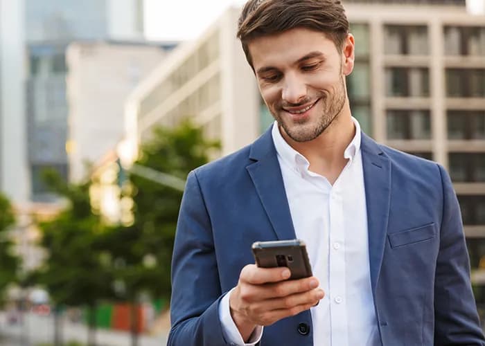 Homme d'affaires utilisant un smartphone à l'extérieur.