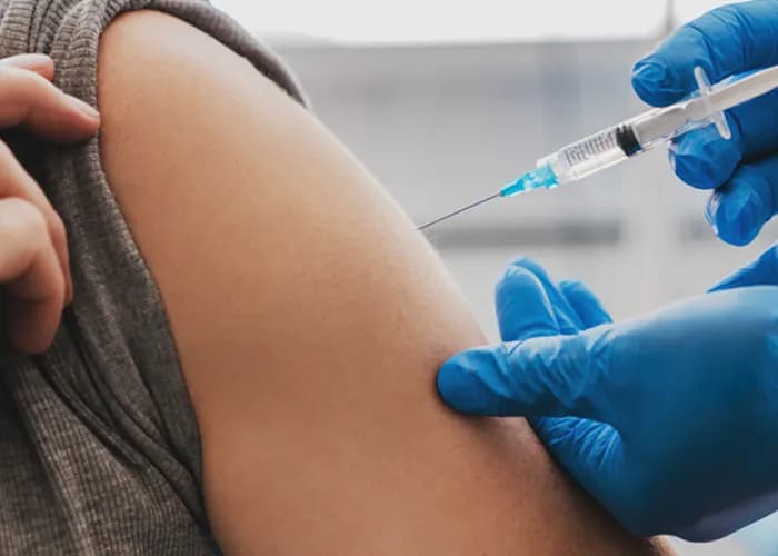 A vaccination being administered into a person's upper arm.