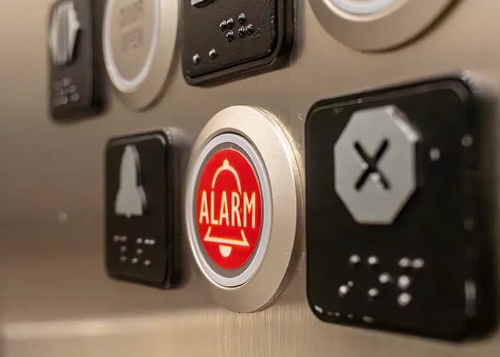 Close-up of red alarm button on elevator control panel.