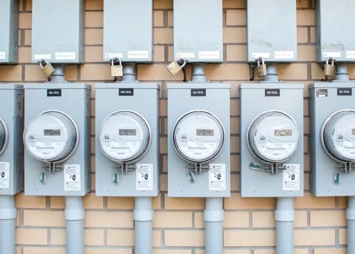 A row of electricity meters mounted on a brick wall.