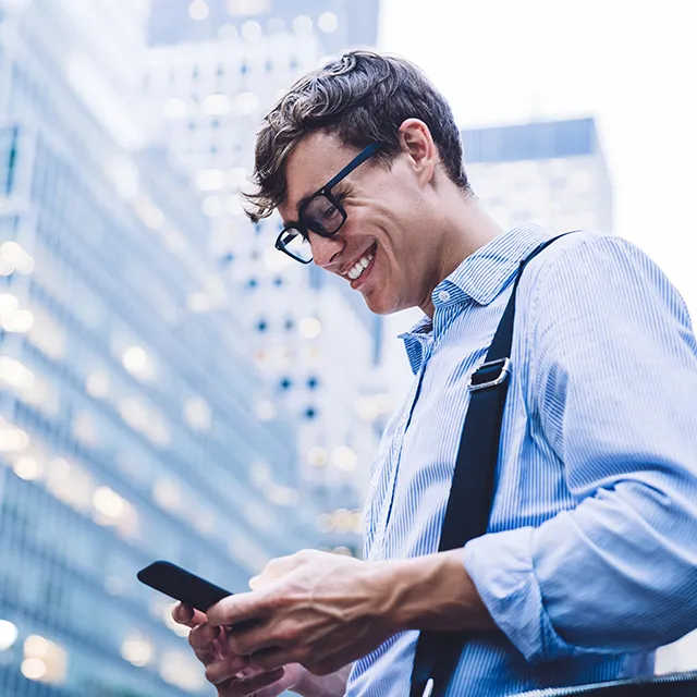 a young man in eyeglasses texting on a phone